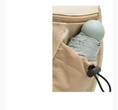 Side pocket of the beige backpack holding a folded umbrella