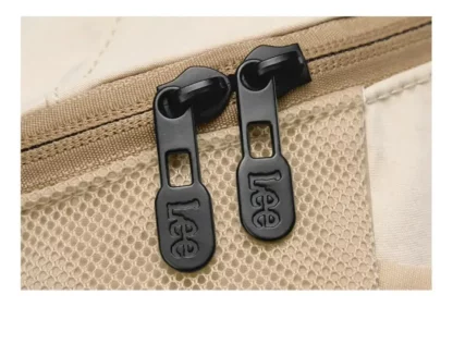 Close-up of the black zip pulls on the beige backpack