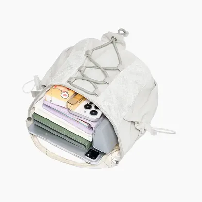 Open off-white backpack holding a tablet, notebooks and a phone