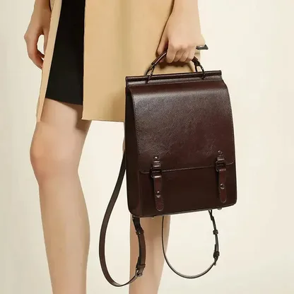 Hand holding the vintage leather backpack by its top handle