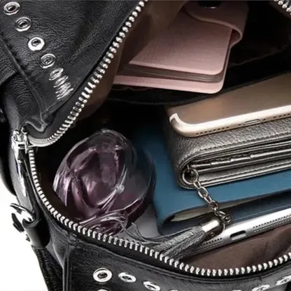 Black leather backpack open, with a notebook, a wallet and a phone inside