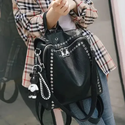 Woman holding the black riveted leather backpack by its top handle