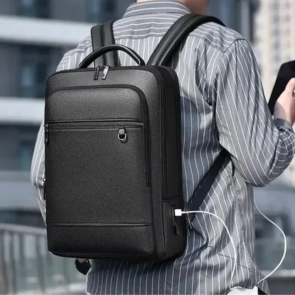 Man wearing the black faux leather laptop backpack with a USB cable plugged in