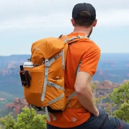 Hiker seen from behind wearing the orange backpack above a canyon